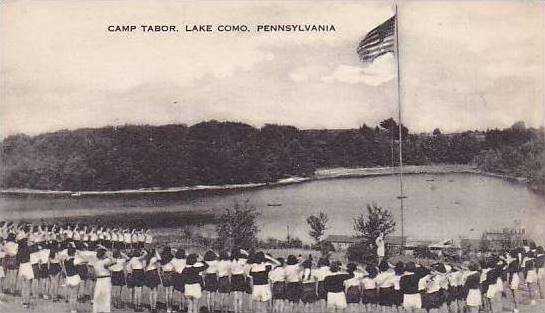 A postcard with a photograph facing Fork Mountain Pond of a group of people saluting an American flag and the title "Camp Tabor, Lake Como, Pennsylvania"