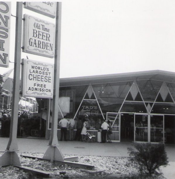 Photograph of the Wisconsin Pavilion at the 1964 World's Fair, with signs stating "Old Time Beer Garden" and "World's Largest Cheese, Free Admission"